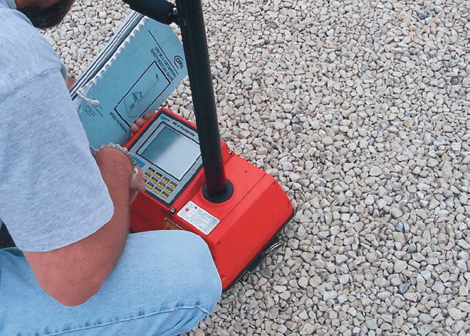 Figure 4. A nuclear density test gauge on compacted No. 57 aggregate is operated in backscatter mode with the probe (black vertical rod) in the up position because it cannot penetrate open-graded aggregates.